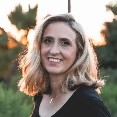 profile picture of a smiling woman in shallow focus wearing a black top